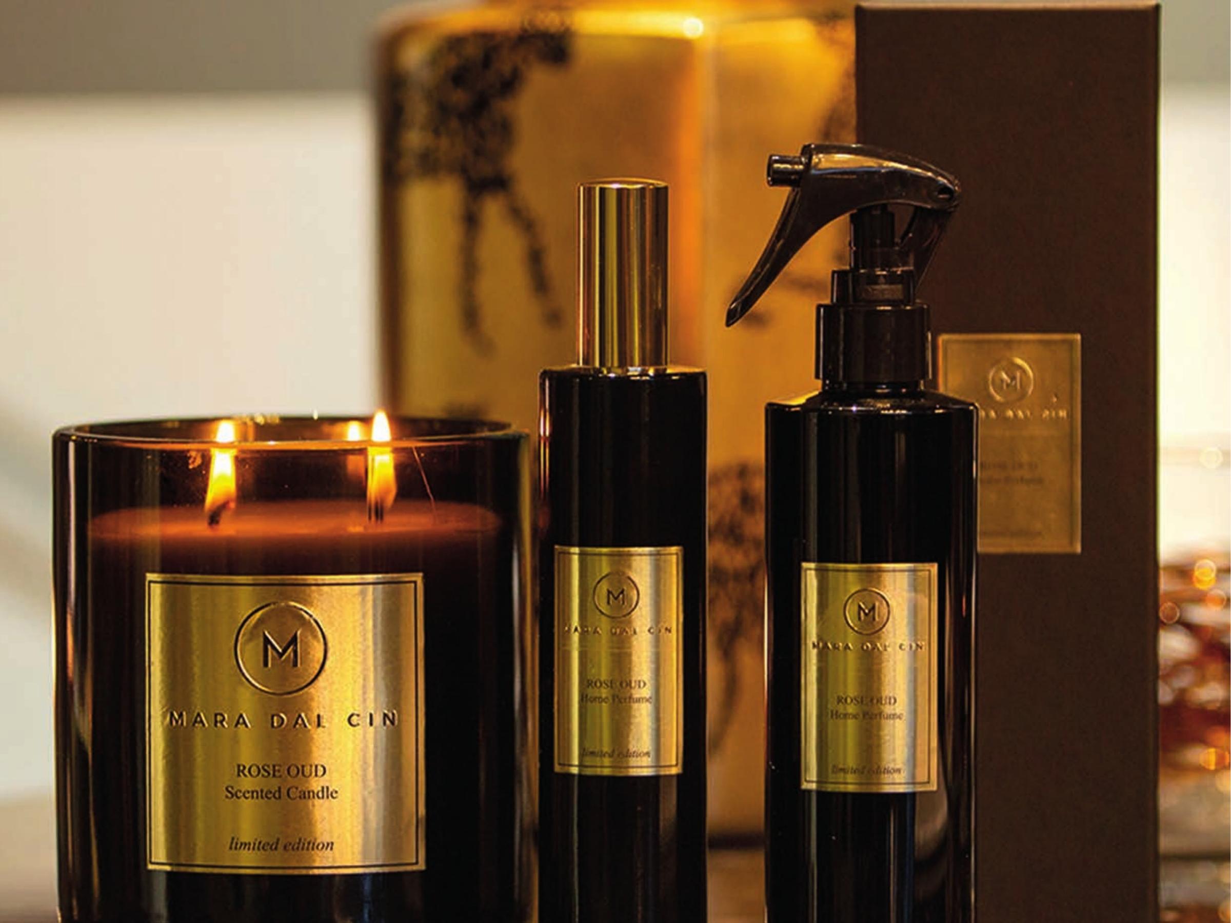La candela profumata Rose Oud accesa, accanto ai profumi per ambiente